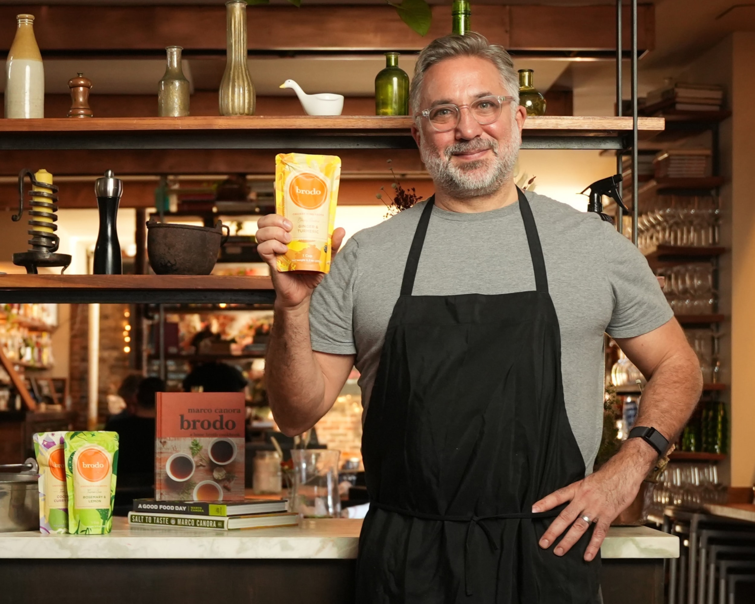 Le propriétaire de Brodo Broth Company pose dans la cuisine du restaurant avec un produit Brodo Broth.